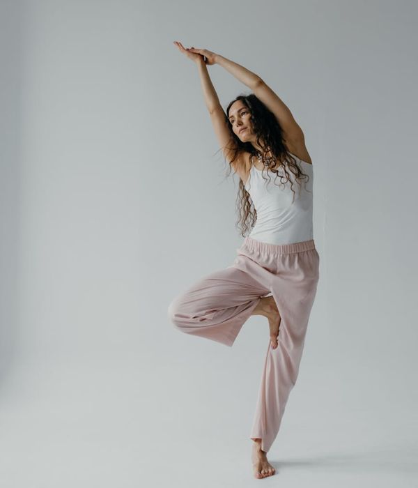 Woman in a mindful movement pose inside a minimalist studio.